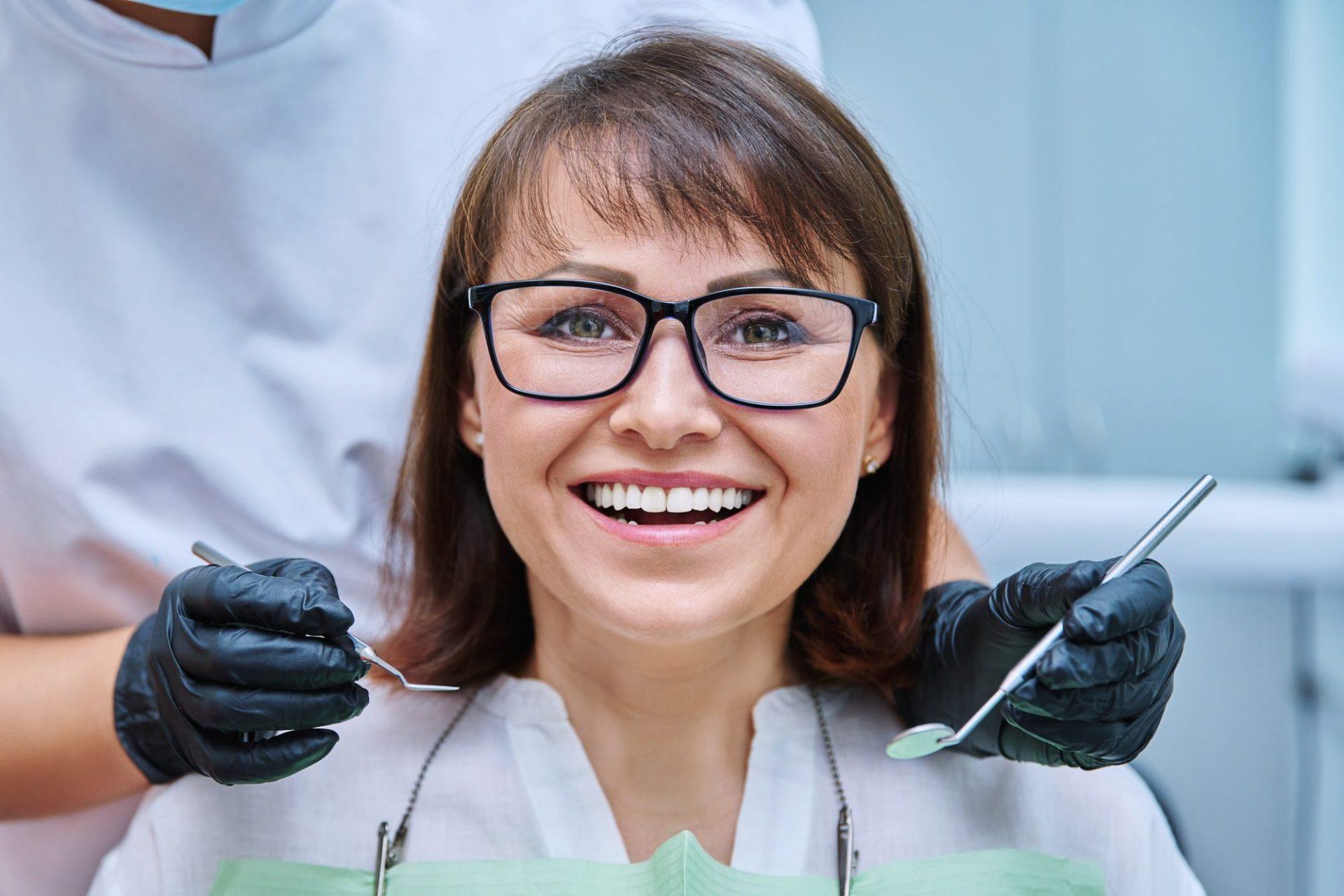 mature woman with teeth in dentistry with hands with dentist examination tools